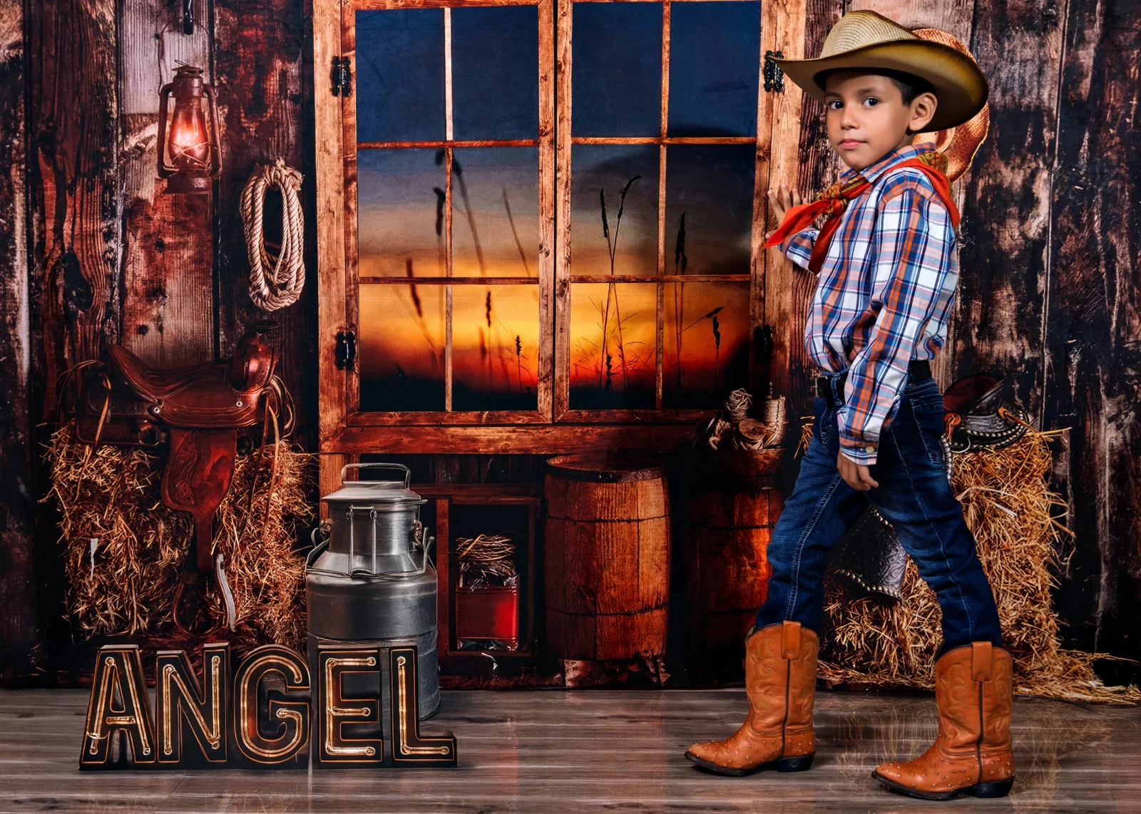 Niño con sombrero y botas en un escenario de temática vaquera.