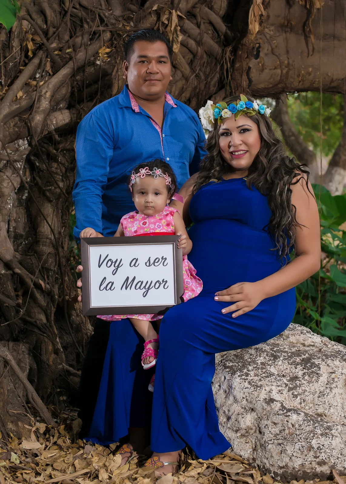Retrato familiar de maternidad junto a un árbol.