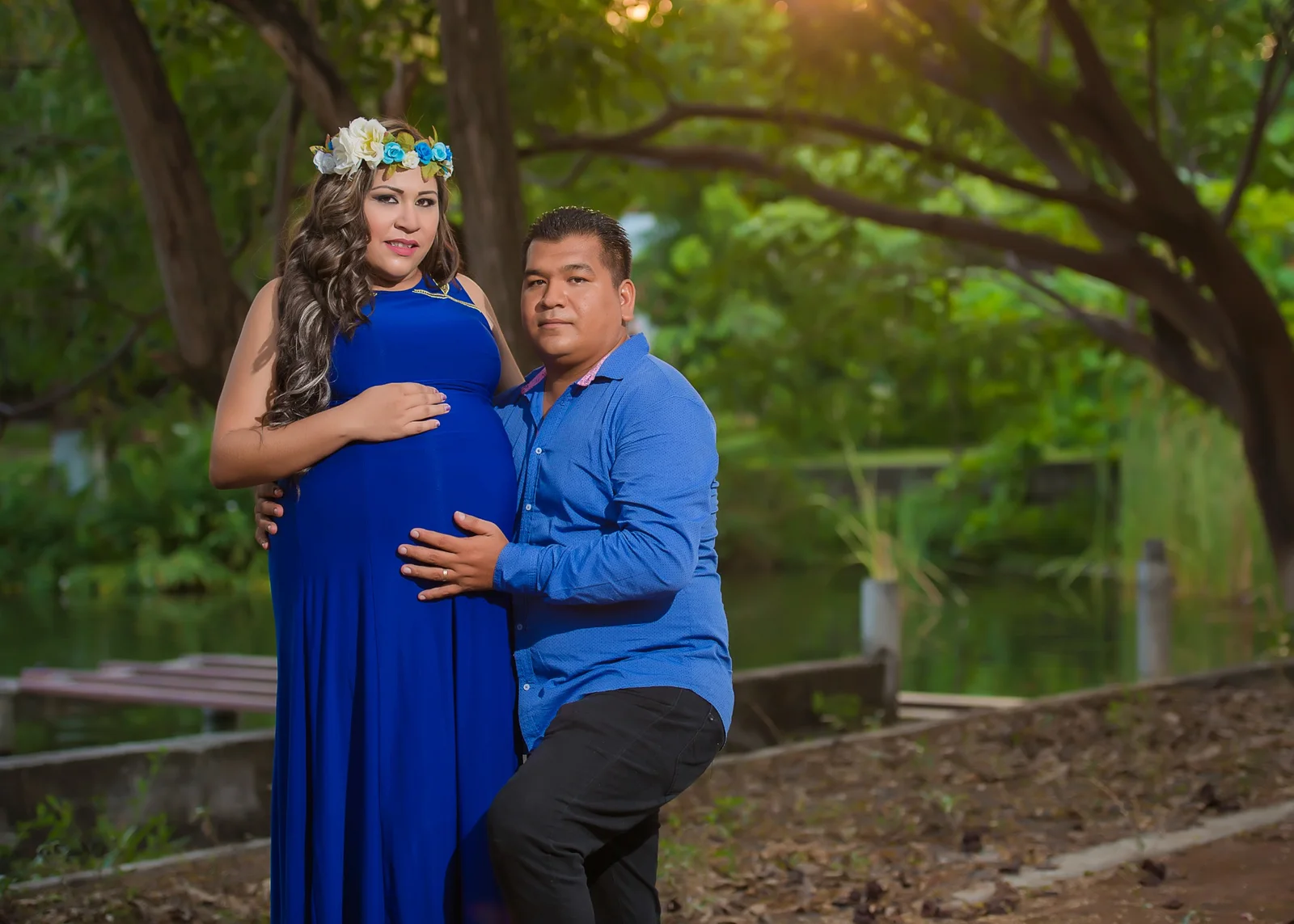 Pareja en sesión de maternidad junto a un lago.
