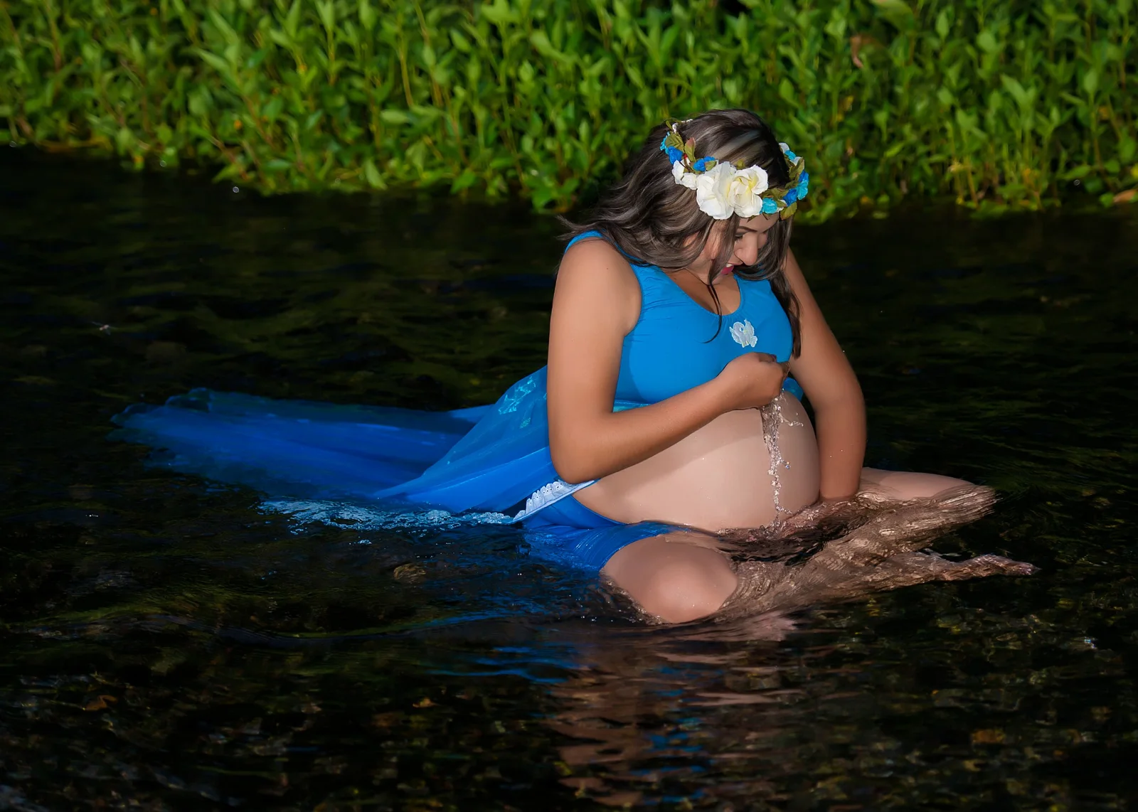 Retrato de maternidad dentro del agua con vestido azul.