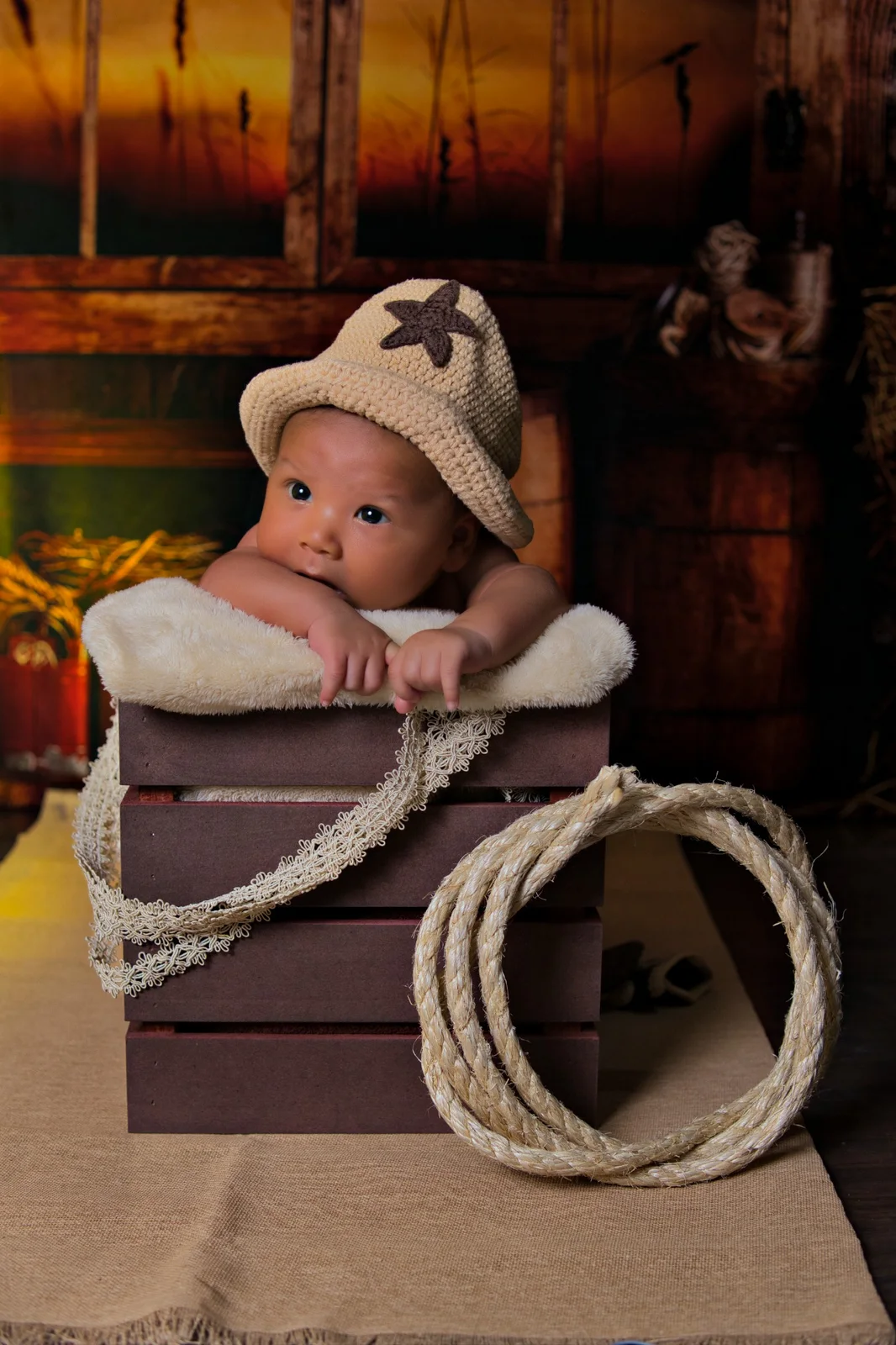 Bebé con sombrero tejido en una sesión newborn de estilo western.