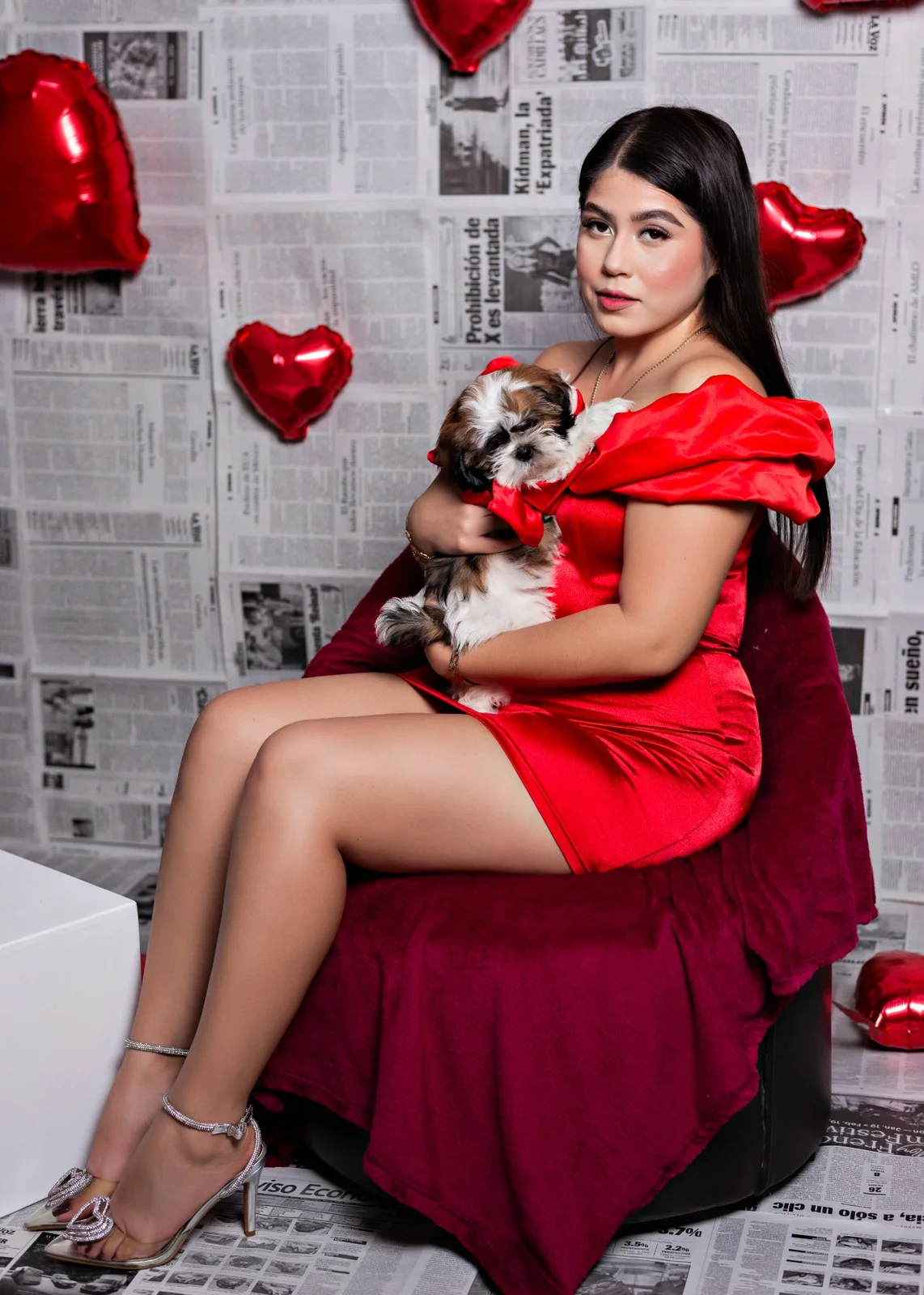 Retrato casual de mujer con vestido rojo sosteniendo a su mascota en escenario de San Valentín.